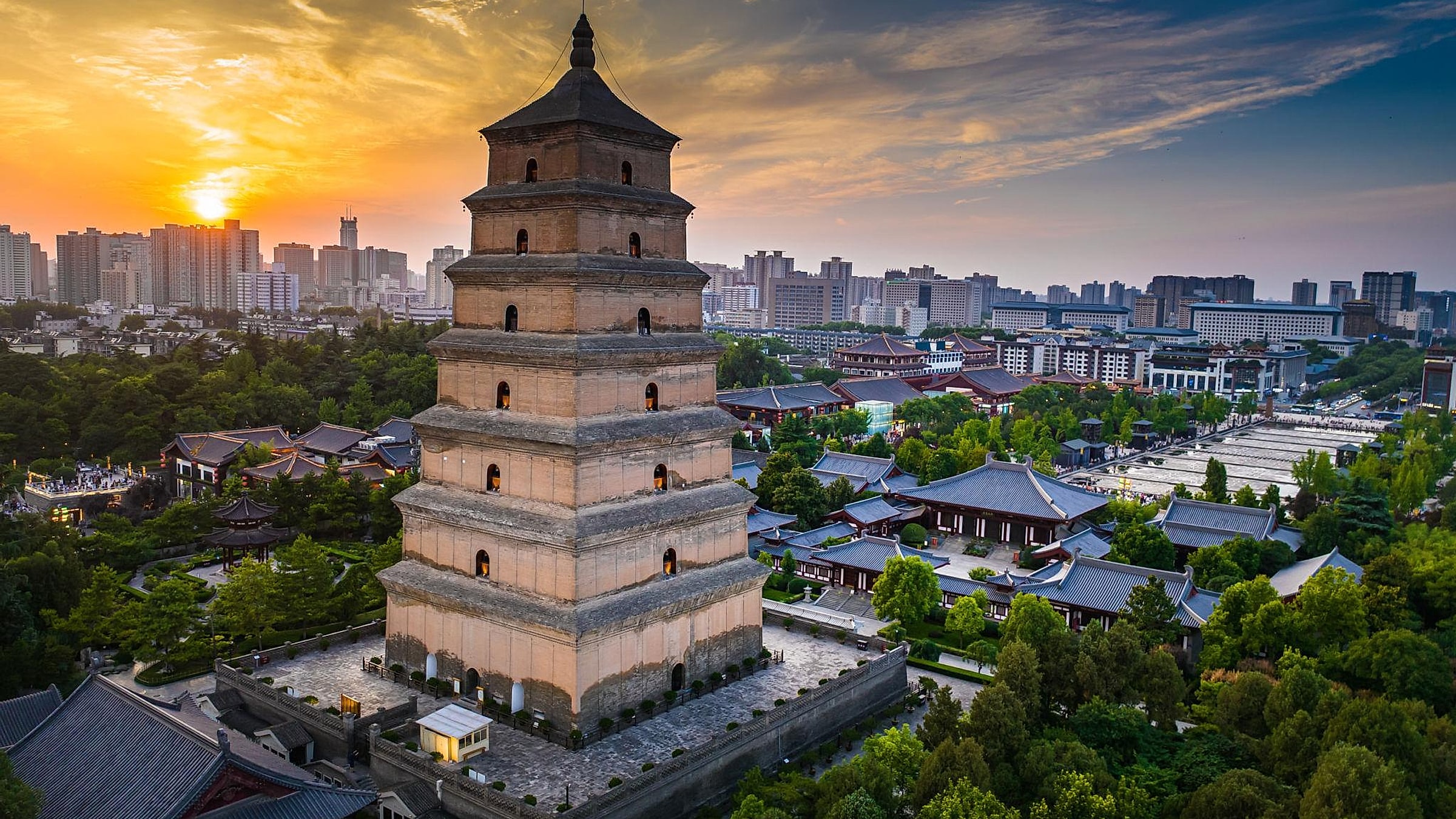 Aerial view of the Big Wild Goose Pagoda at sunset with the Da Ci'en Temple complex and modern Xi'an skyline behind