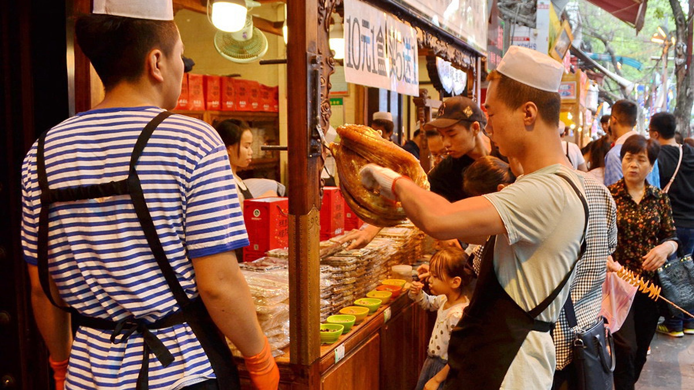 Muslim Quarter street food vendor handing a flatbread to a customer, with skewers and snacks on display