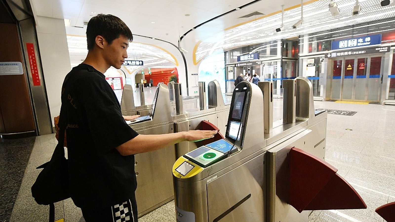Man scanning his palm at a modern Chinese metro turnstile — Alipay also works for transit via QR or palm scan (刷掌乘车, Beijing 2025)