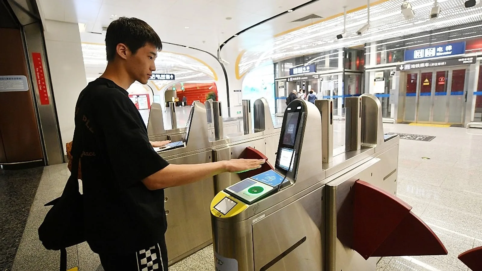 Мужчина сканирует ладонь на современном турникете китайского метро — Alipay также работает для транзита через QR или сканирование ладони (刷掌乘车, Пекин 2025)