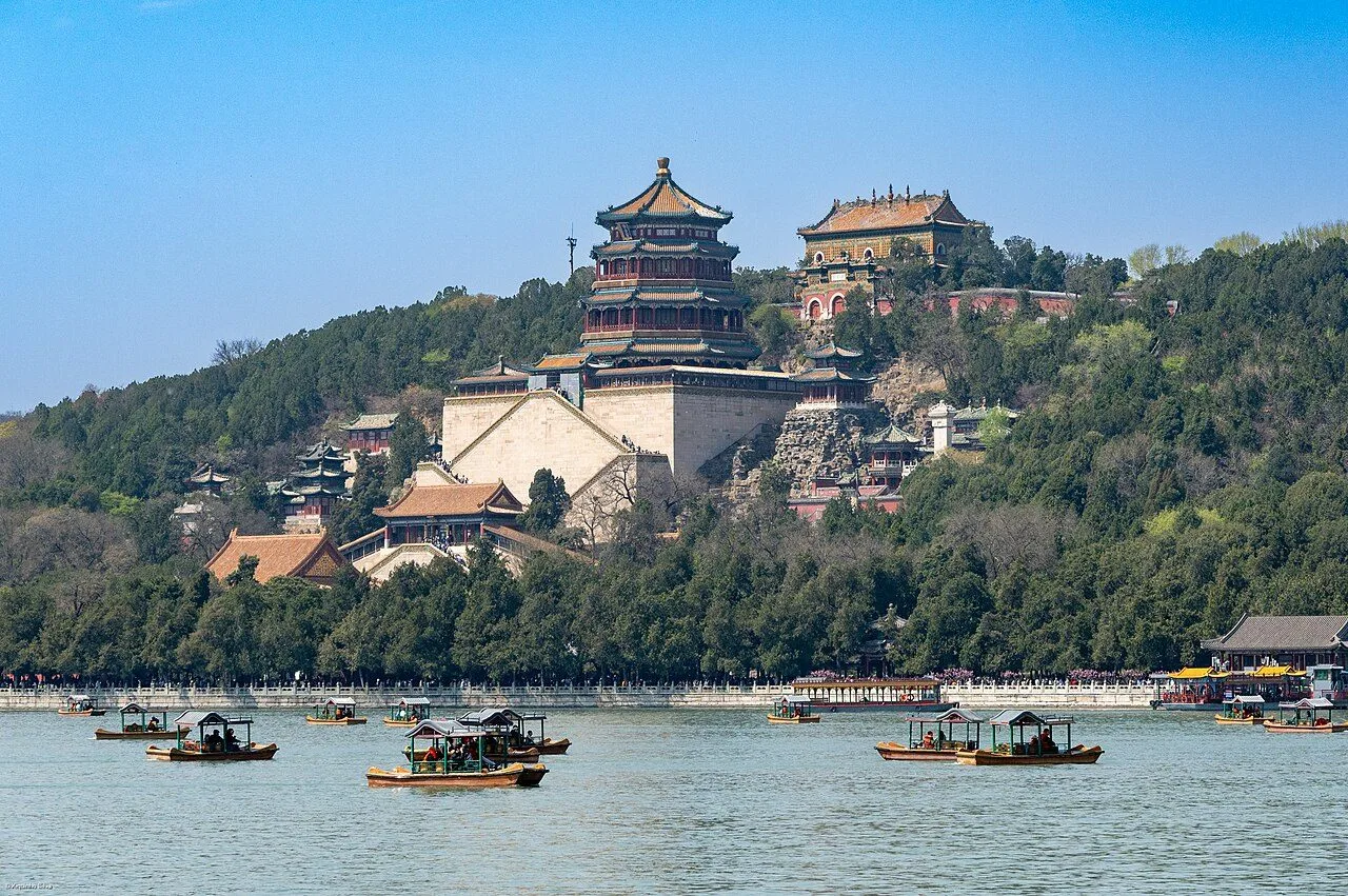 Aerial view of Kunming Lake at the Summer Palace, with traditional Chinese pavilions along the shore and the modern Beijing skyline in the background