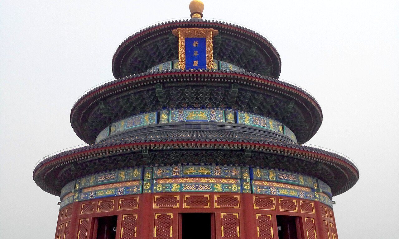 The Hall of Prayer for Good Harvests, a triple-eaved circular building in deep blue tiles, photographed from below against a winter sky