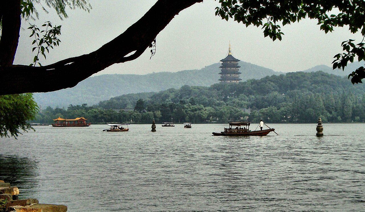 West Lake at sunset with the Leifeng Pagoda in the background and traditional wooden boats on the water