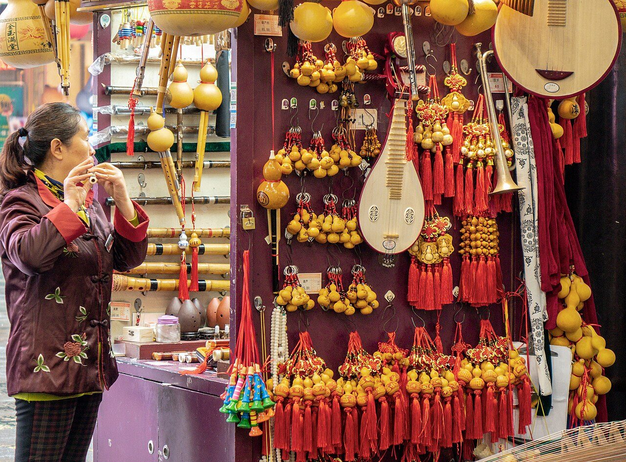 A vendor at the Yuyuan Bazaar near Yu Garden, with hanging gourds and traditional Chinese instruments