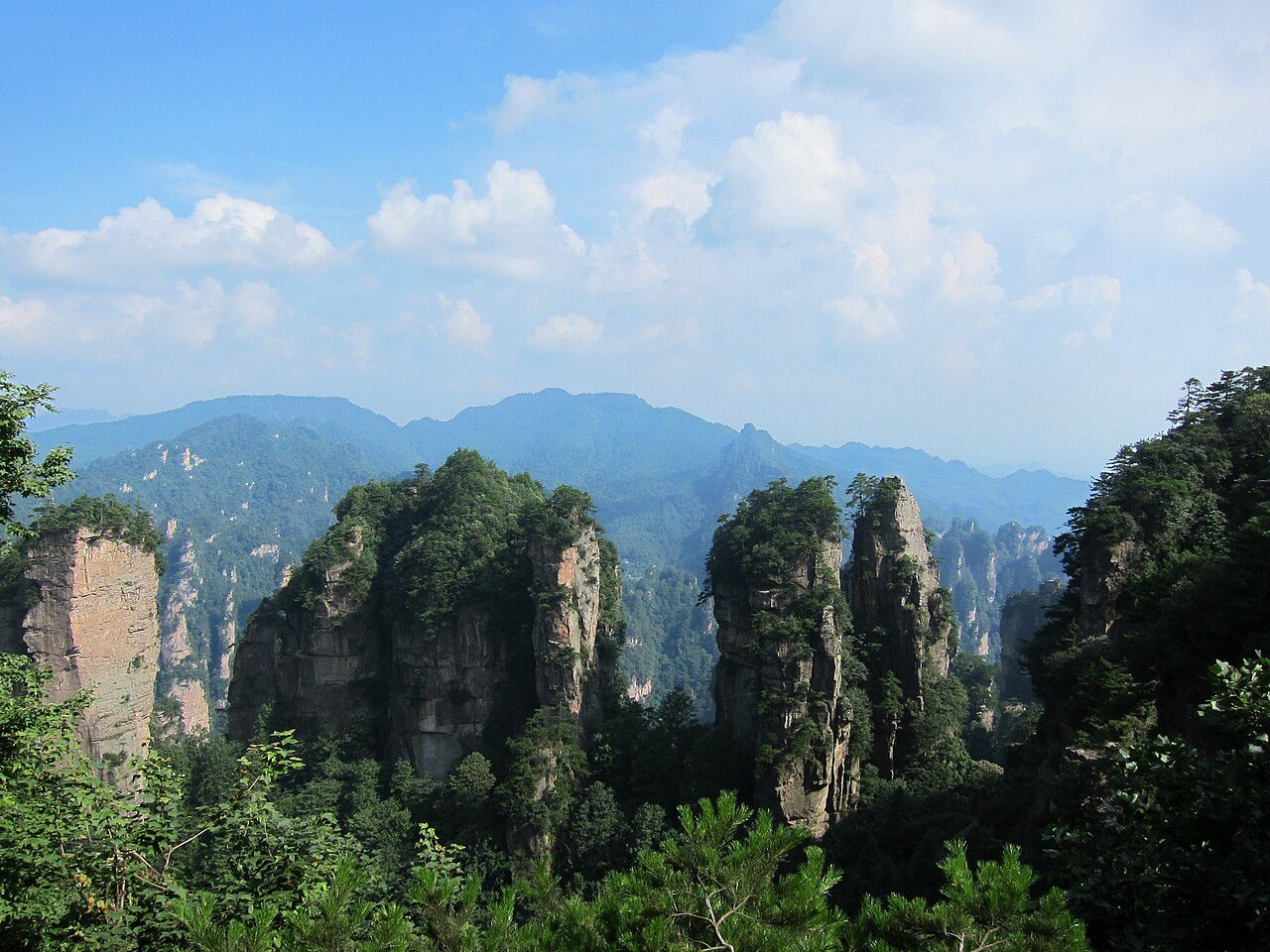 Towering sandstone pillars of Zhangjiajie National Forest Park, with pine trees growing from the rock faces and mist in the valleys
