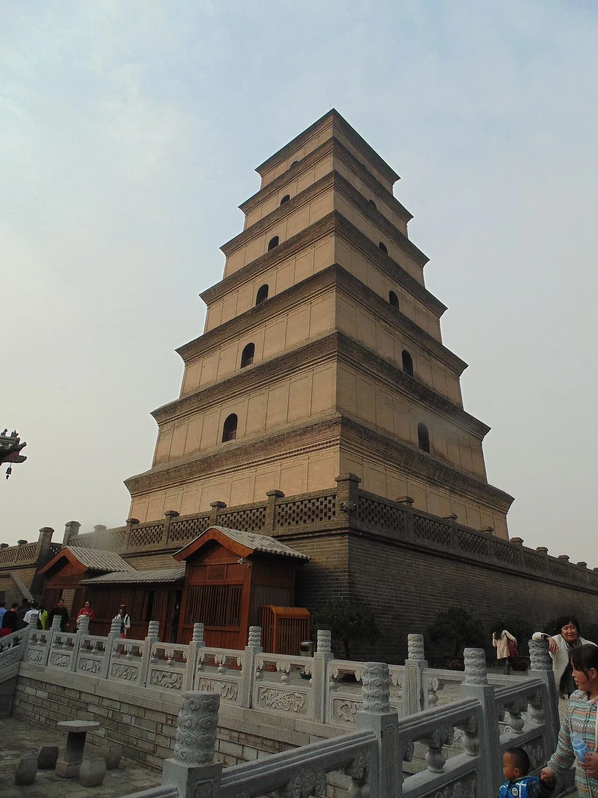 The full Big Wild Goose Pagoda in Xi'an — a 64-meter, 7-story Tang-dynasty brick pagoda (built 652 AD, rebuilt 704 AD), viewed from below with the wooden gatehouse at its base and visitors at the foot of the steps