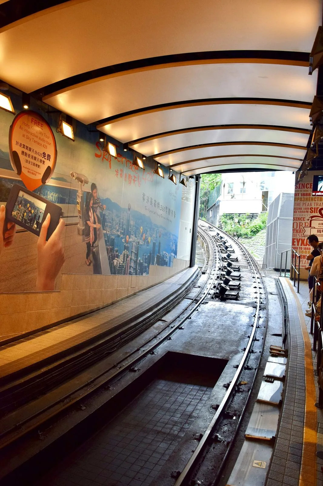 The iconic Peak Tram tracks climbing up Victoria Peak in Hong Kong — the funicular railway that has carried visitors up the 396m of vertical climb since 1888, the wooden-slatted track and the steep gradient (the world steepest funicular at 4-27 degrees) visible in close-up, the 6-minute ride from Central that delivers visitors to the top of Hong Kong Island, the tram that until 2021 was the only way for the public to reach the Peak