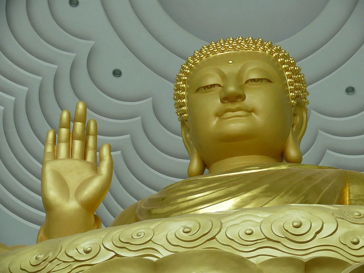 The smiling Budai (Laughing Buddha) statue inside Famen Temple, an elderly man kneeling in prayer on the cushion in front of the statue, capturing a quiet devotional moment at the temple