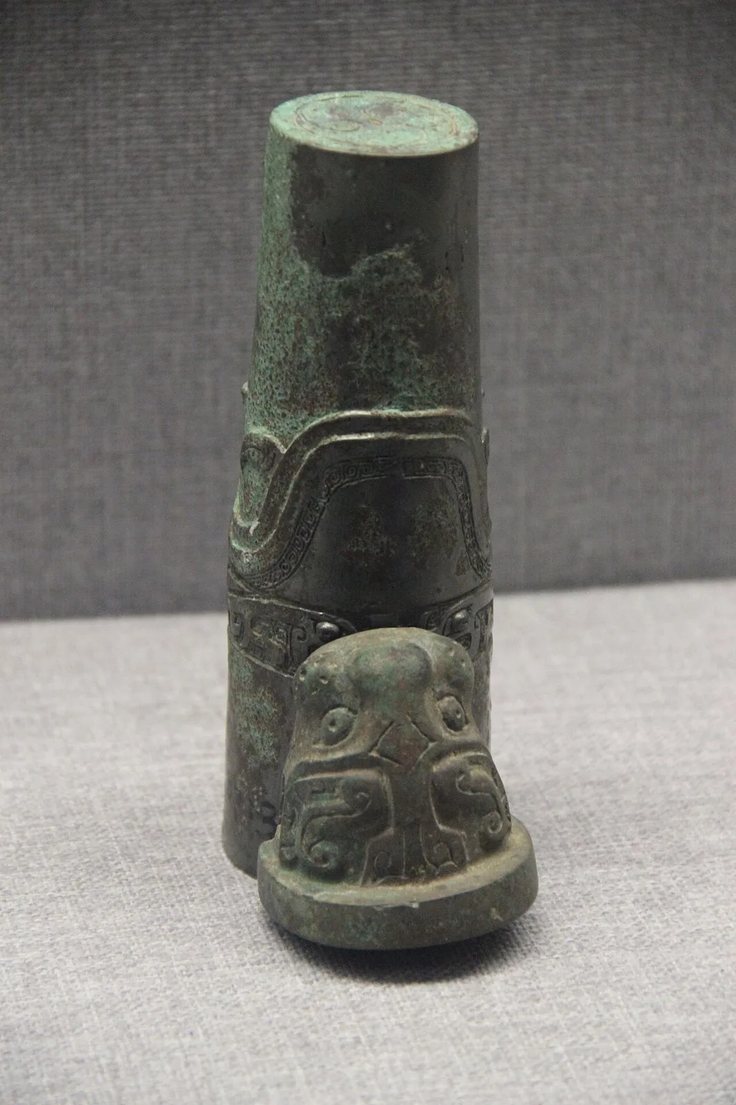 A Western Zhou bronze chariot axle hub with intricate taotie patterns and a small animal-head finial — one of the famous Western Zhou Dynasty (1046-771 BC) artifacts in the Luoyang Museum collection, found at the Zhou Dynasty royal cemetery in Luoyang