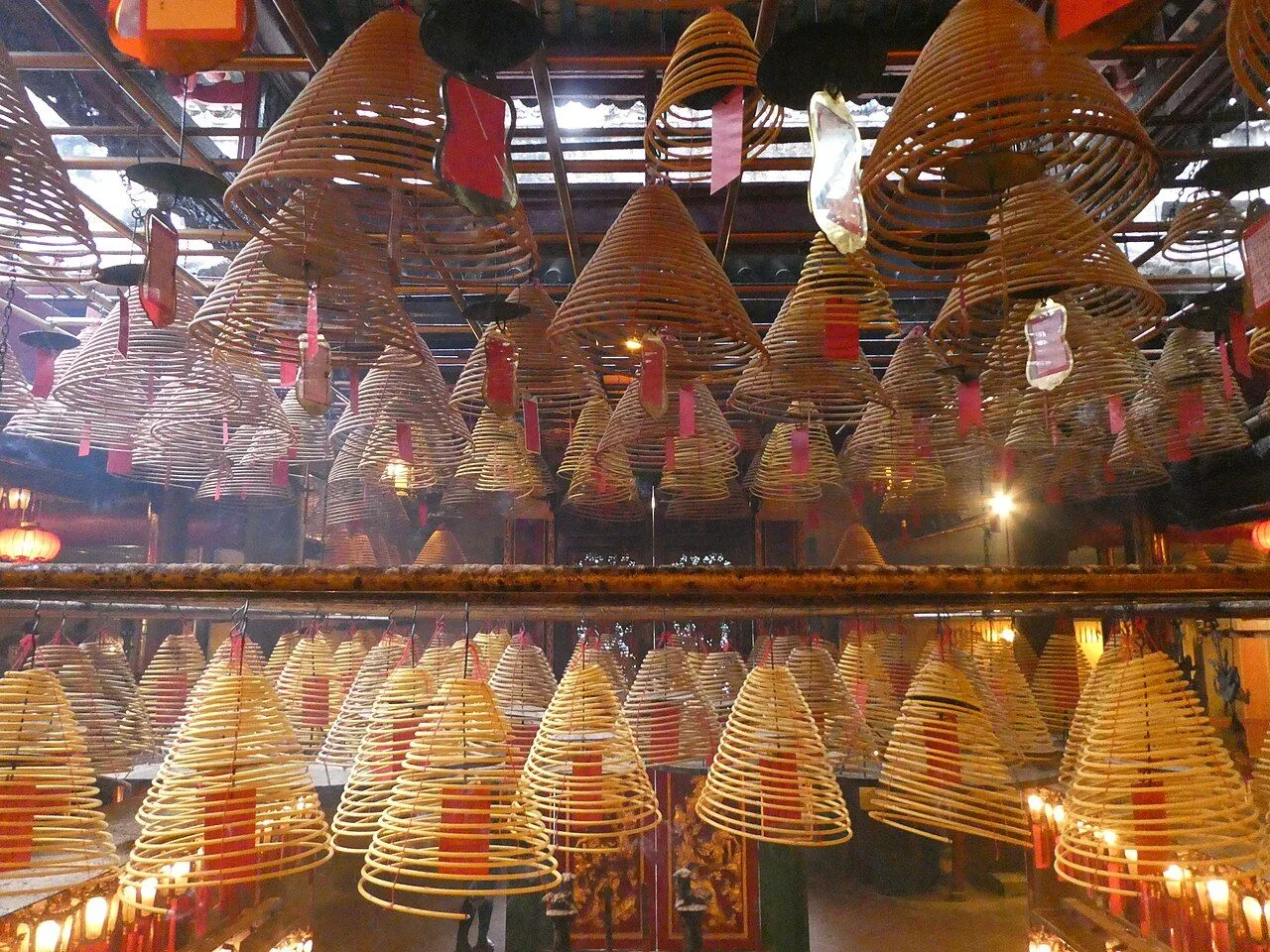 The iconic ceiling of Man Mo Temple — hundreds of giant spiral incense coils hanging from above, slowly burning and filling the temple with smoke that creates the mystical atmosphere this 19th-century temple is famous for. The coils can burn for days or weeks at a time, symbolizing prayers ascending to the heavens
