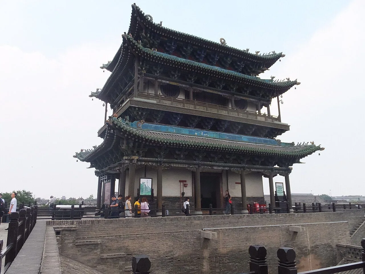 The North Gate (北门) of Pingyao Ancient City — a towering three-tiered gatehouse with traditional curved green-tile roof sitting atop the massive brick city wall, the main ceremonial entrance to the walled city built in 1370 during the Ming dynasty and the most photographed of Pingyao’s six gates