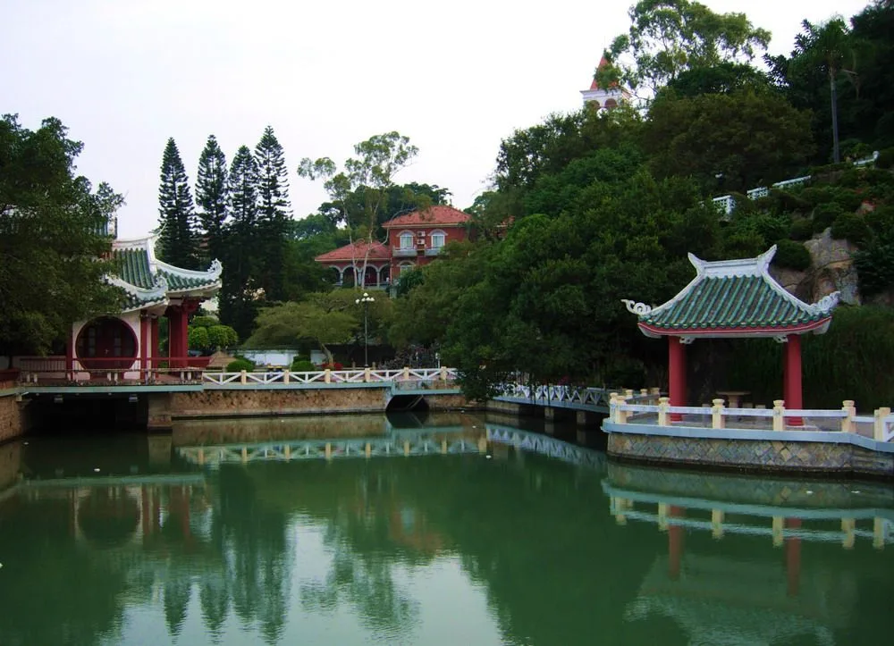 Shuzhuang Garden on Gulangyu Island — the piano-shaped garden built by a Taiwanese businessman in 1931, with traditional pavilions and bridges reflected in the green lake water — the most-photographed garden on the island