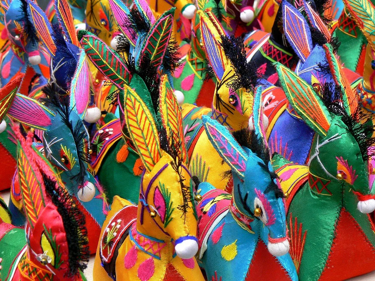 Handmade embroidered donkeys sold as souvenirs in the Xi'an Muslim Quarter — these colorful fabric donkeys with bright fabric ears and sequined eyes are the signature craft of the Hui Muslim artisans of the bazaar street. The donkey has cultural significance on the Silk Road where caravans carried goods