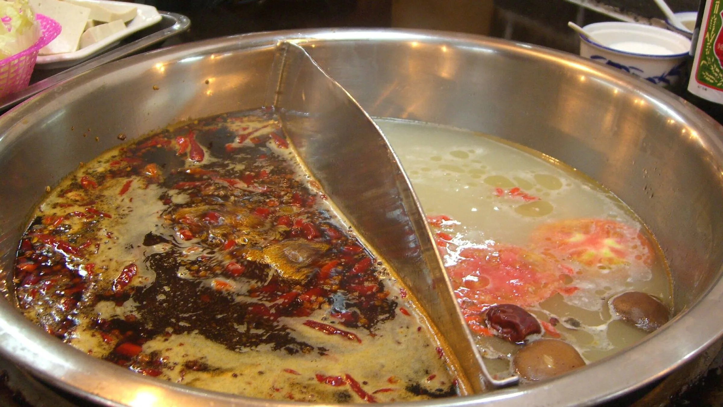 一面に辛い赤スープともう一面に透明な骨スープがある成都スタイルの鸳鸯火鍋、材料を調理する準備完了