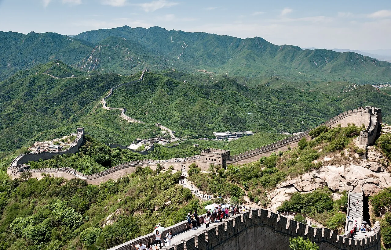 Group of foreign tourists exploring the Great Wall of China on a guided tour with a Chinese tour guide