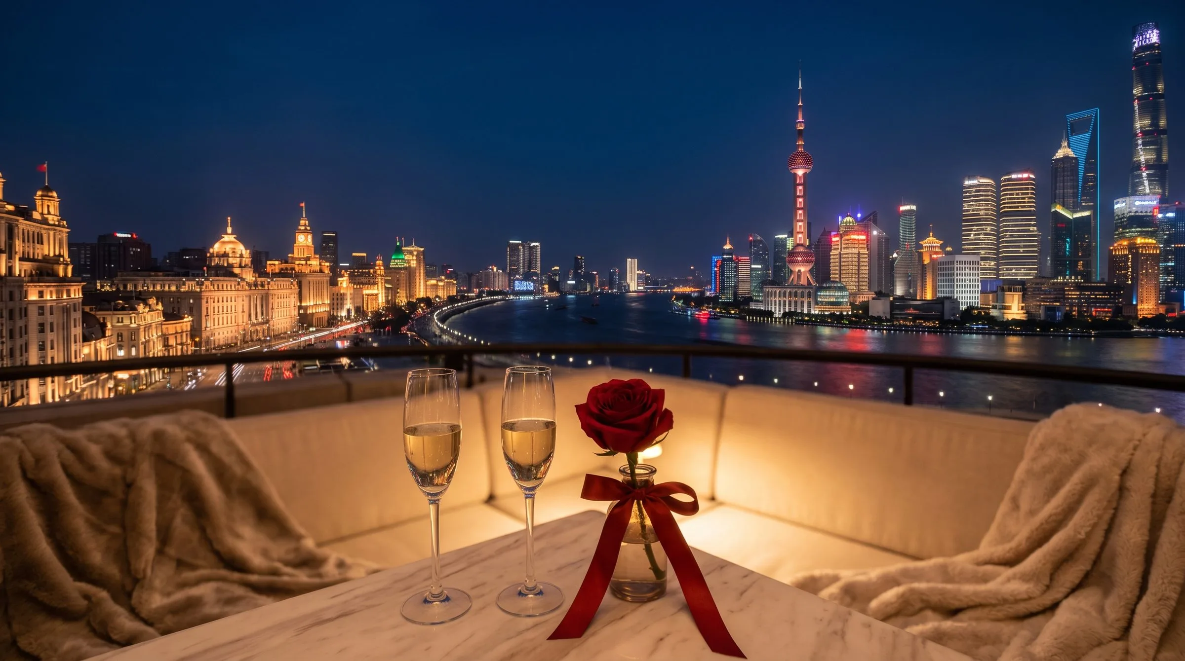 Two glasses of champagne on a hotel balcony overlooking a Shanghai Bund night skyline