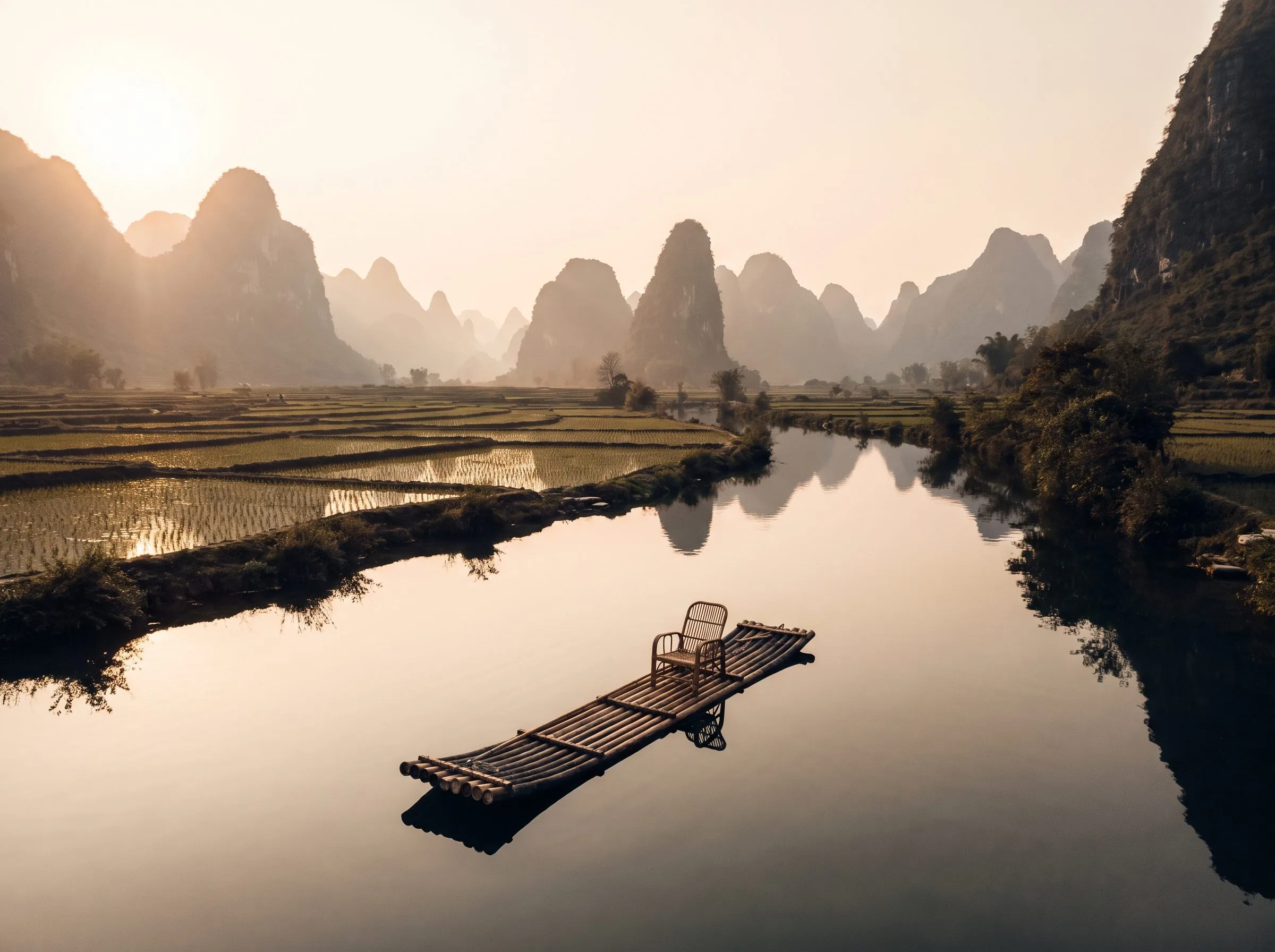 Iconic Guilin Yangshuo karst landscape with misty limestone peaks and a bamboo raft on a still river at golden hour