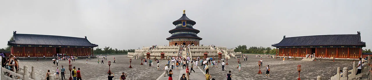 The Hall of Prayer for Good Harvests at the Temple of Heaven in Beijing — the iconic 38m three-tiered circular blue-tiled hall with a golden finial, the white marble Circular Mound Altar in the foreground and a few worshippers walking across the wide flagstone plaza under soft afternoon light, a UNESCO World Heritage Site completed in 1420