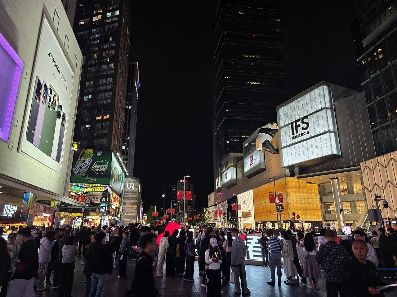 Chunxi Road at night, packed with pedestrians, neon billboards, and the iconic IFS panda sculpture climbing the side of the building.