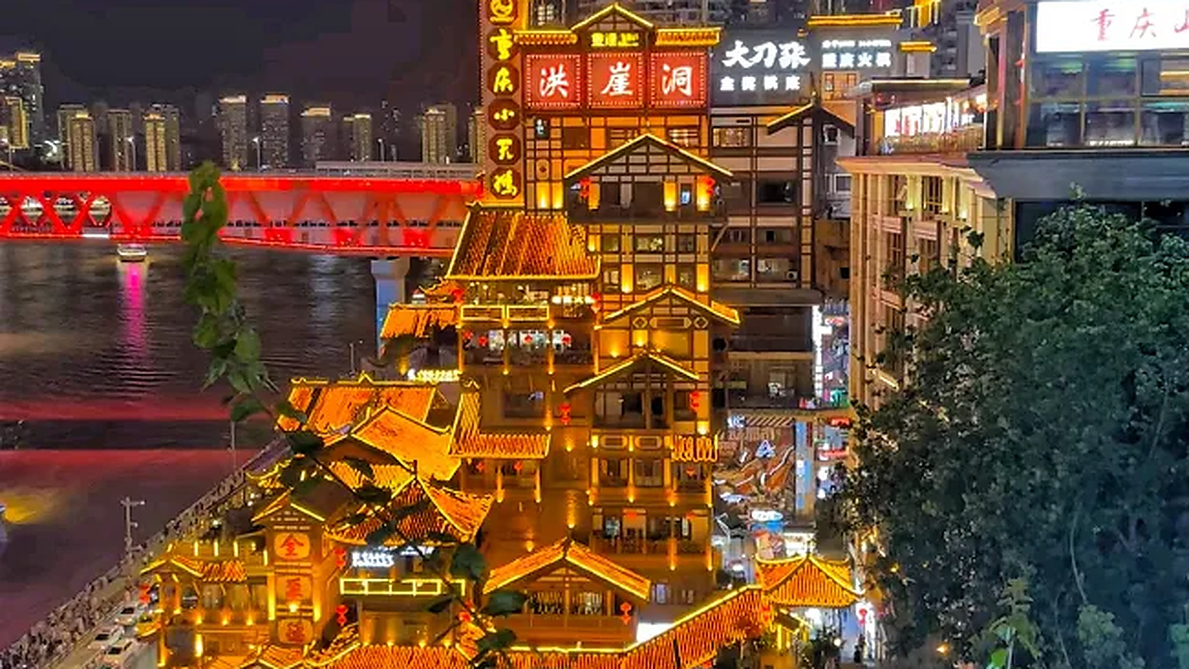 Hongya Cave — 11-story stilted house complex on the Jialing River, lit gold at night.