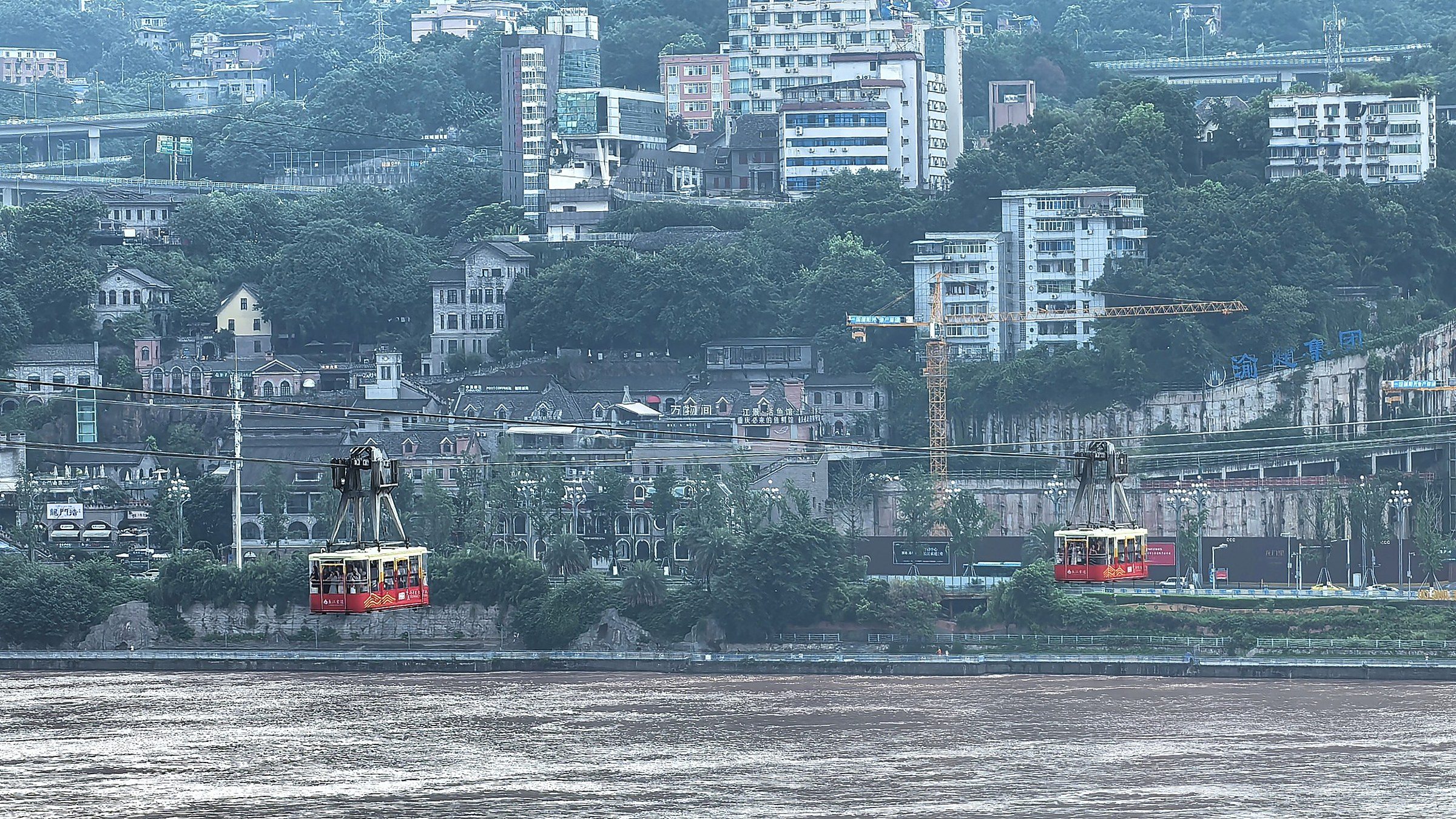 Yangtze River Cable Car crossing the river with hillside apartment buildings in the background, Chongqing