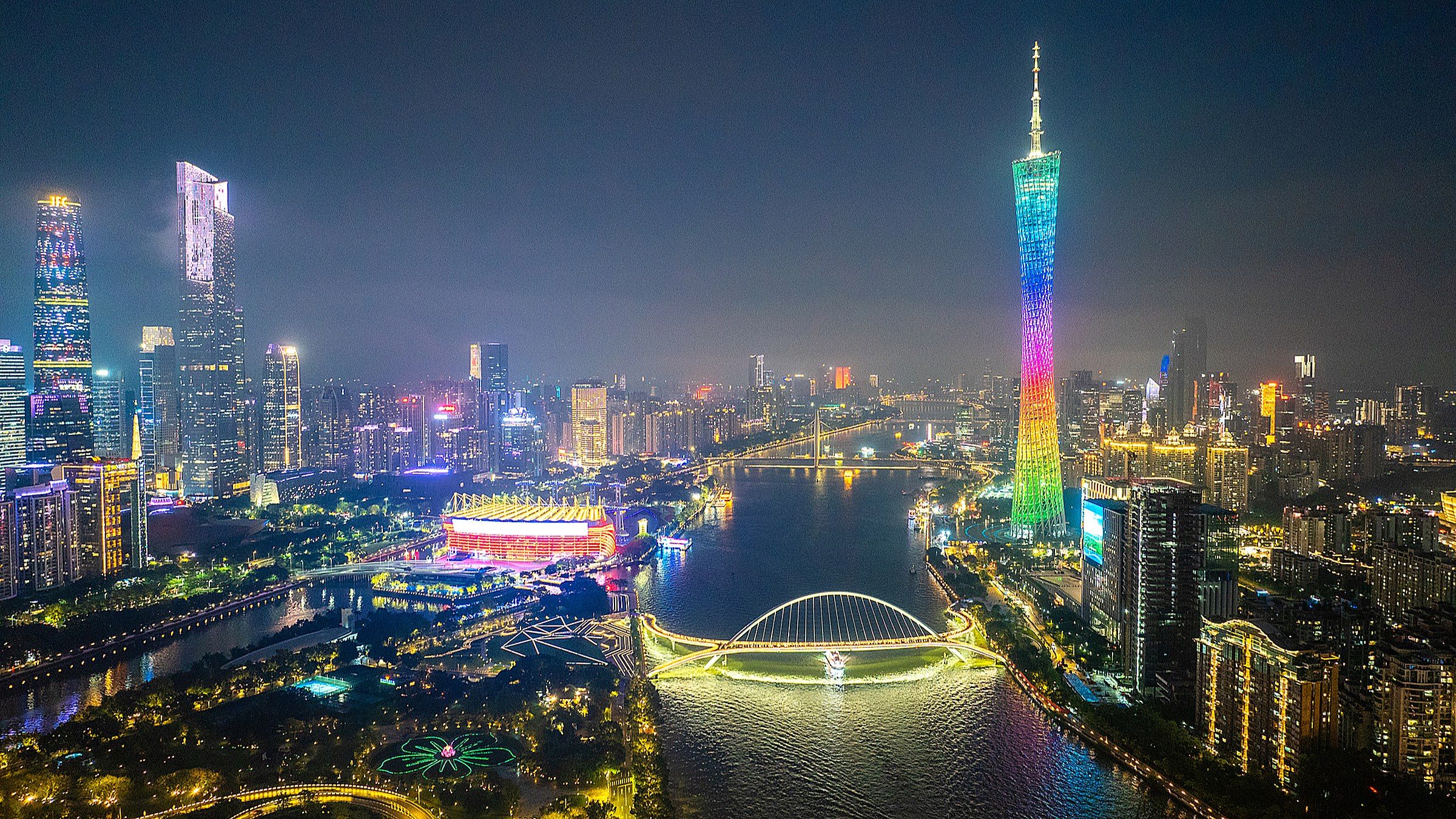 Canton Tower at dusk — a 600m hyperboloid structure lit purple and pink, with the Pearl River in the foreground and Guangzhou's central business district behind