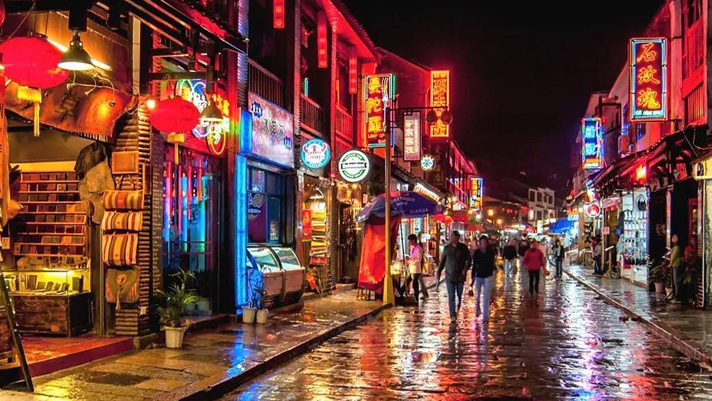 West Street Yangshuo at night — red lanterns strung across the cobblestone street, with crowds of tourists and shop fronts glowing in warm light