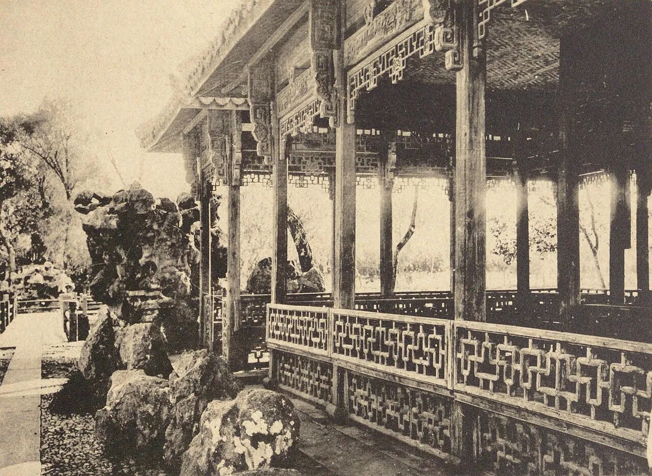 The Wanzi Pavilion on West Lake in Hangzhou, a traditional Chinese wooden pavilion reflected in still water with Taihu rocks in the foreground.