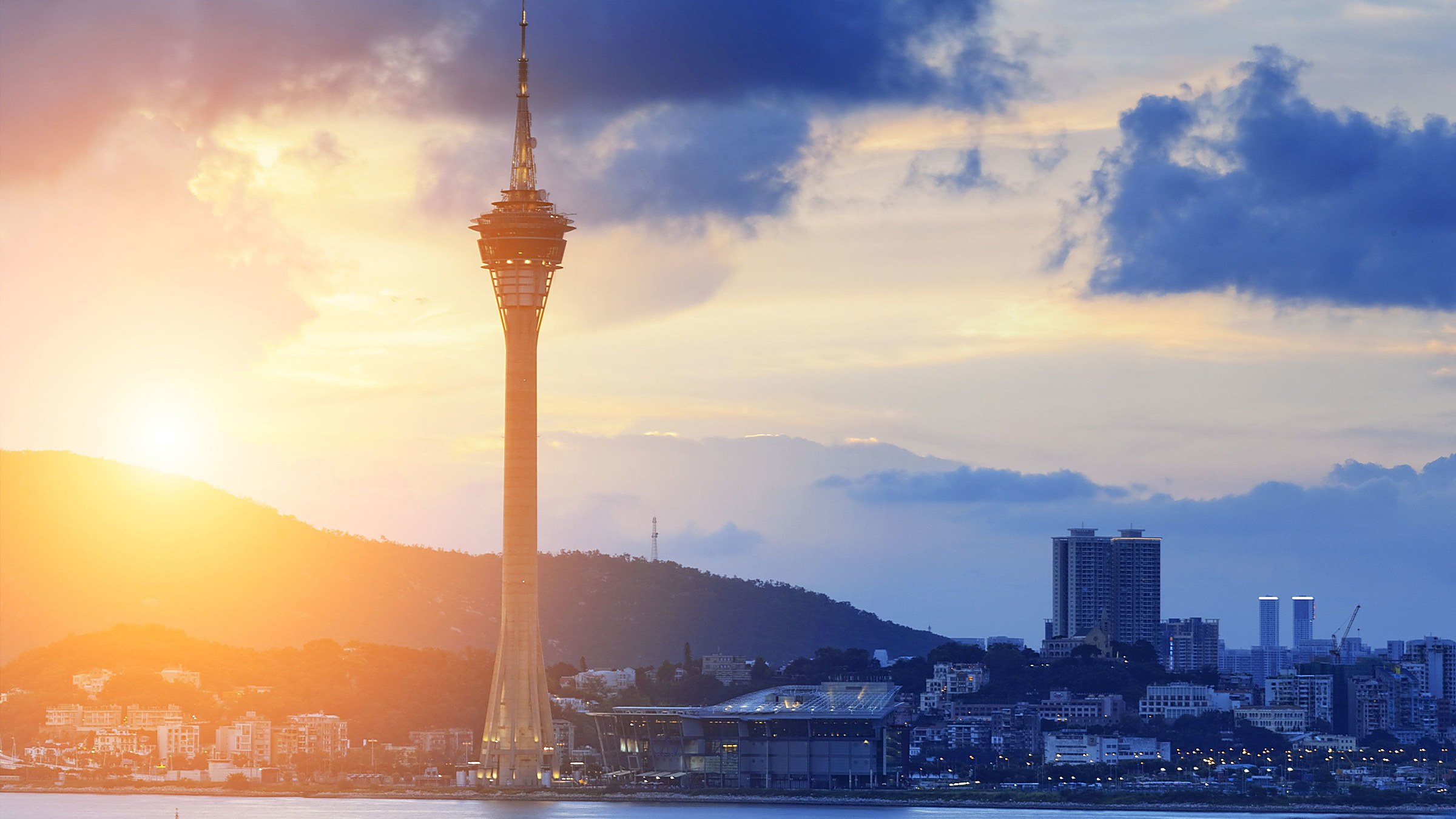 Macau Tower at sunrise, a 338m white needle tower on the south end of the peninsula, with the Cotai Strip in the distance across the water