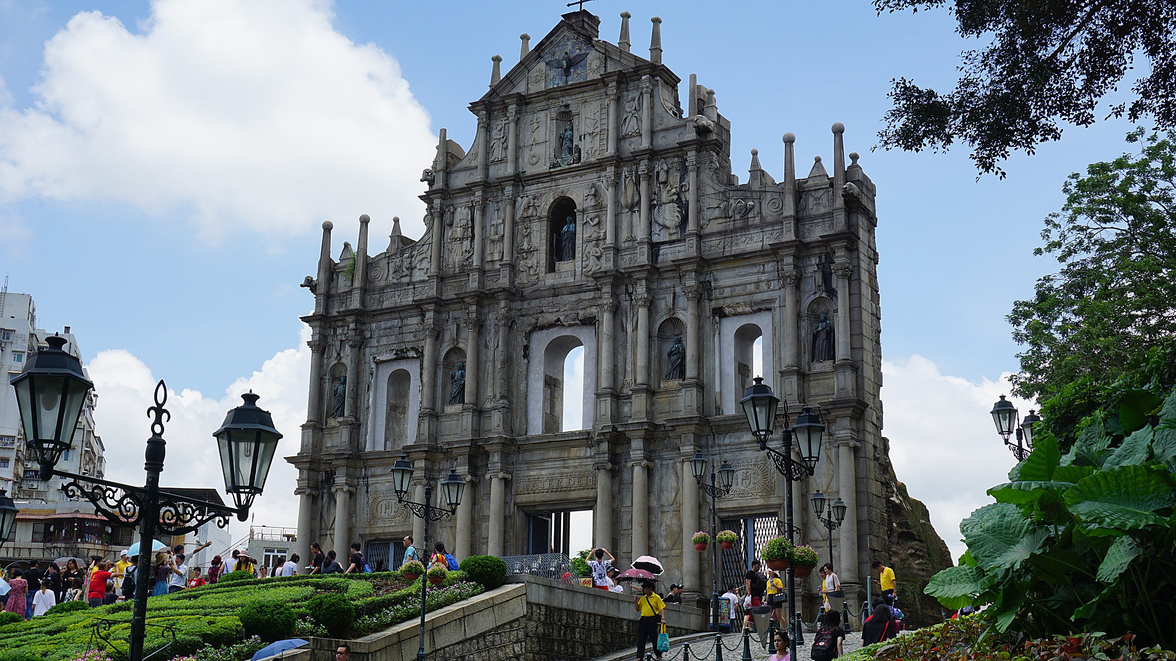 The 17th-century stone facade of the Ruins of St. Paul's in Macau, with five tiers of carved biblical figures and bronze statuary against a blue sky