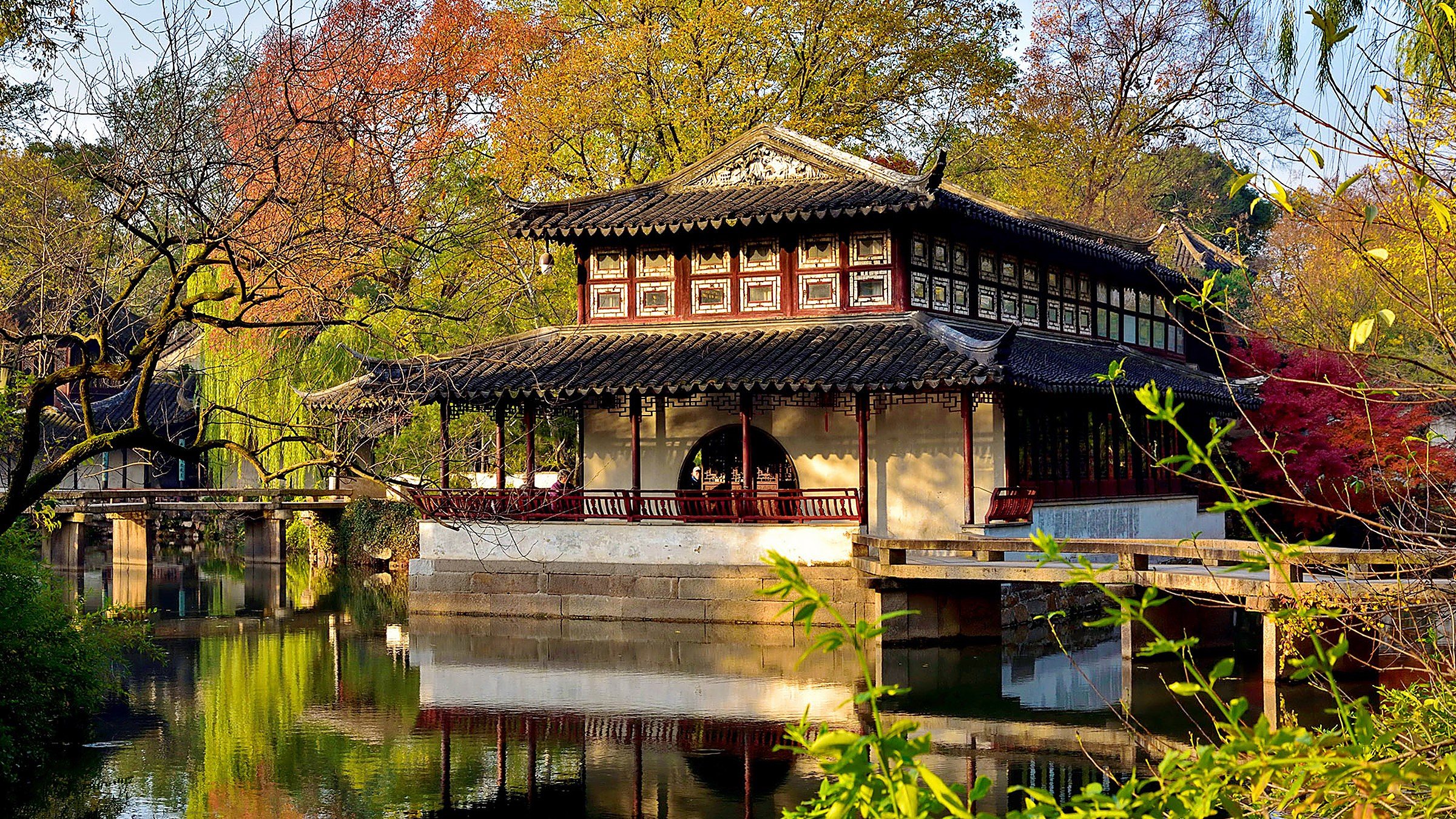 Humble Administrator's Garden — a UNESCO classical Chinese garden with a central pond, white-walled pavilions with dark tile roofs, and 21 distinctively-shaped window frames