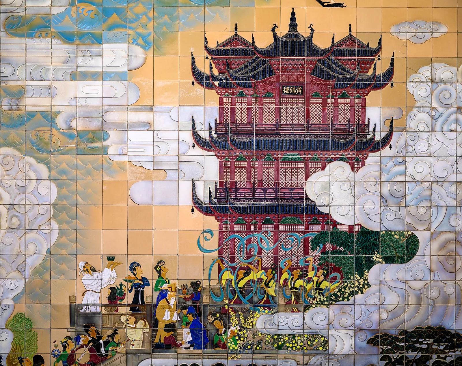 The base of the Yellow Crane Tower in Wuhan, with the five-tiered pagoda's lower levels visible above a wide granite plaza where a crowd of visitors is gathered on a sunny day.