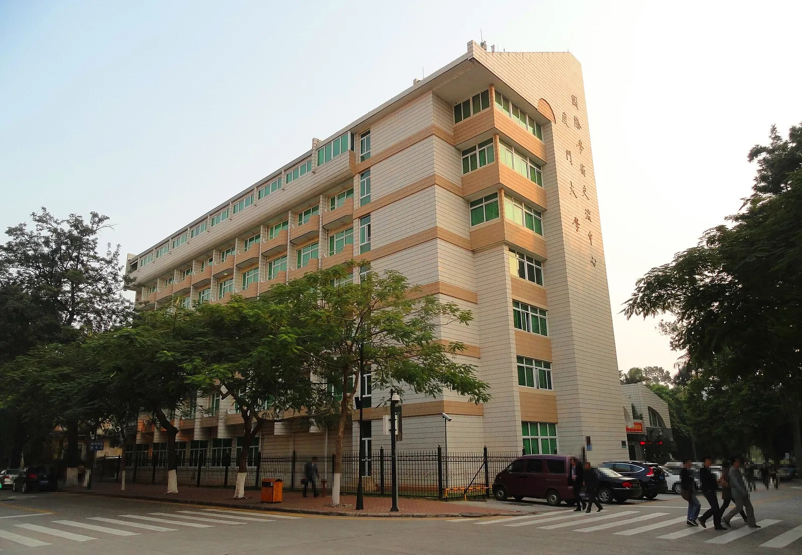 The Shaw Building at Xiamen University, a striking three-storey red-brick and white-stone structure in Minnan-Southeast-Asian style with arched windows and a central bell tower, set on a tree-lined campus.
