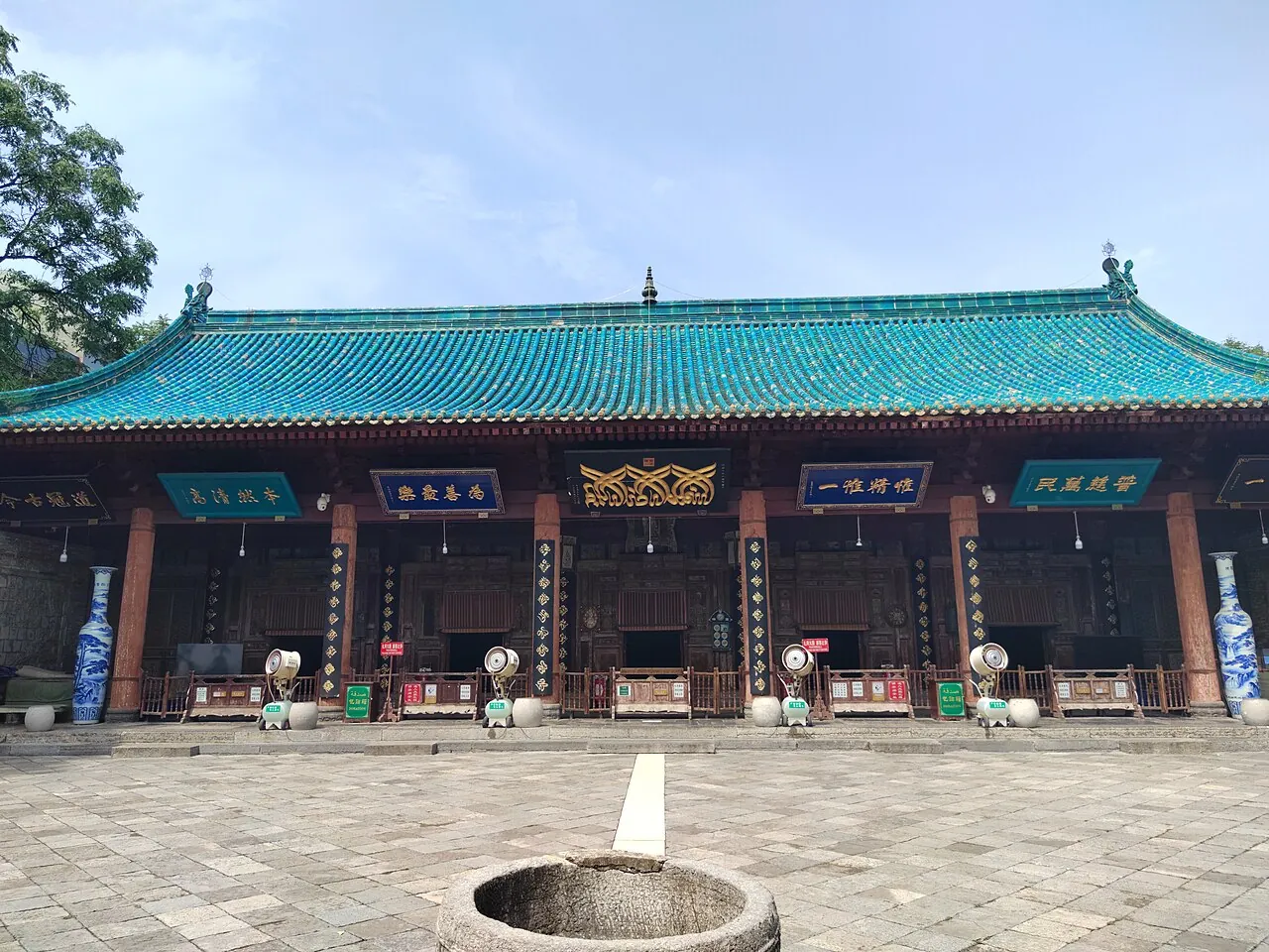 The prayer hall of the Great Mosque of Xi'an, a 14-meter glazed-tile roof in turquoise with Arabic calligraphy panels and a stone-paved courtyard.