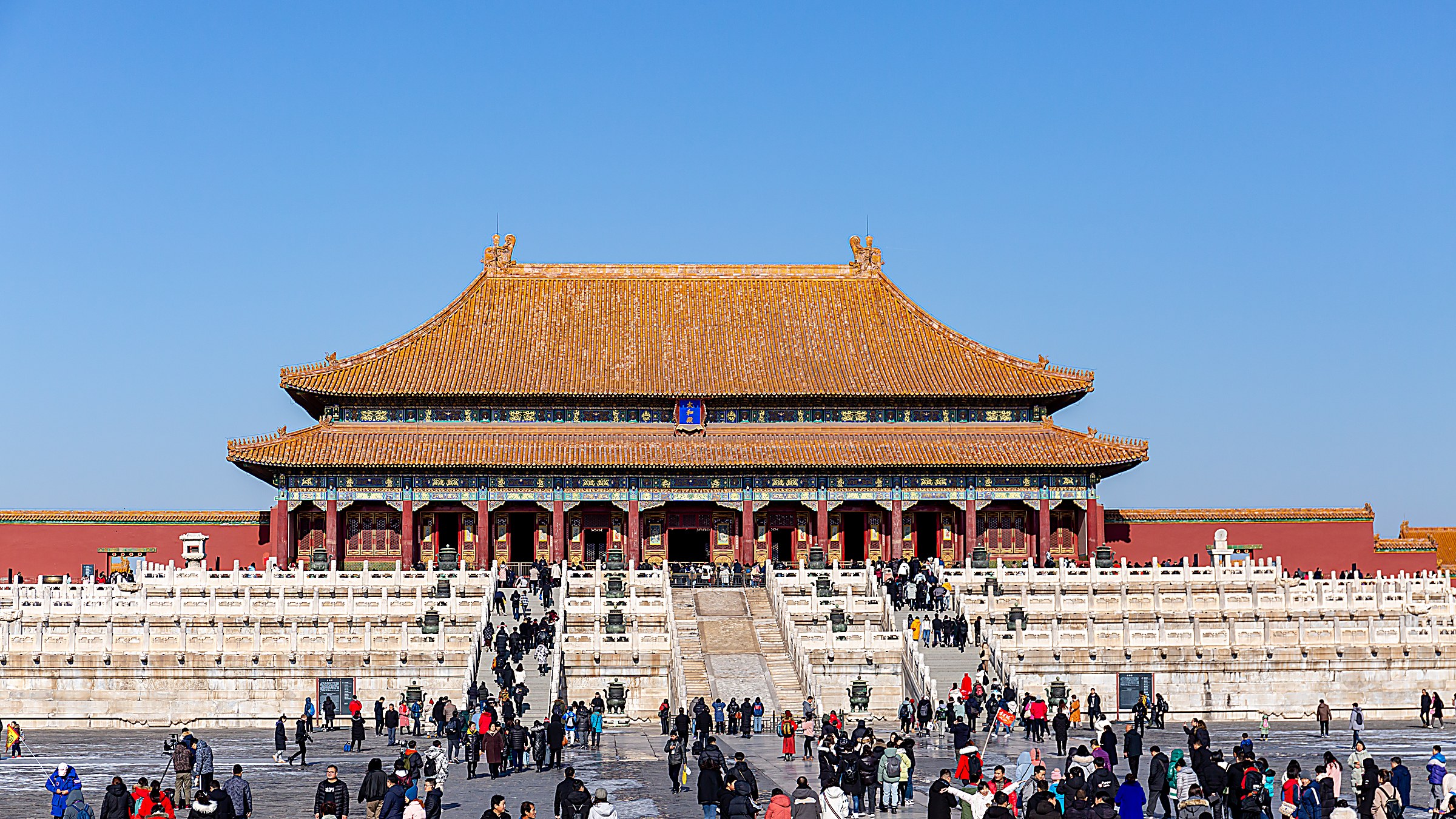Hall of Supreme Harmony in the outer court of the Forbidden City in Beijing, a triple-eaved wooden pavilion with golden glazed-tile roof, white marble terraces, and ceremonial courtyard under a clear blue sky