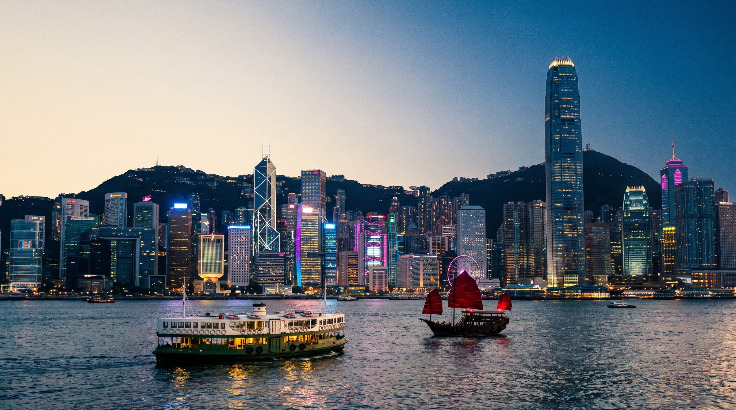 View of Victoria Harbour at dusk from Victoria Peak showing the dense Hong Kong skyline with the IFC tower, Bank of China Tower, and Kowloon waterfront lit up in neon