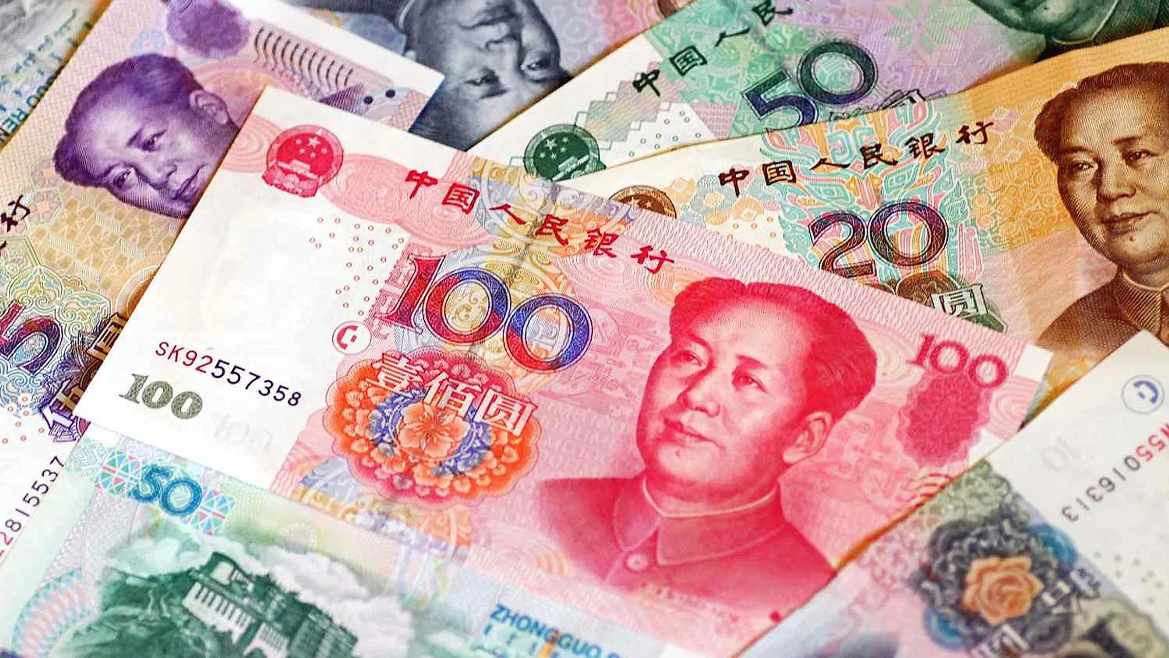 Renkli Çin RMB banknotlarının yayılmış yakın çekimi — gerçek ile sahte banknot arasındaki farkı oluşturan metalik şerit, renk değiştiren rakamlar ve yakadaki kabartma baskıyı karşılaştırmak için kullanın