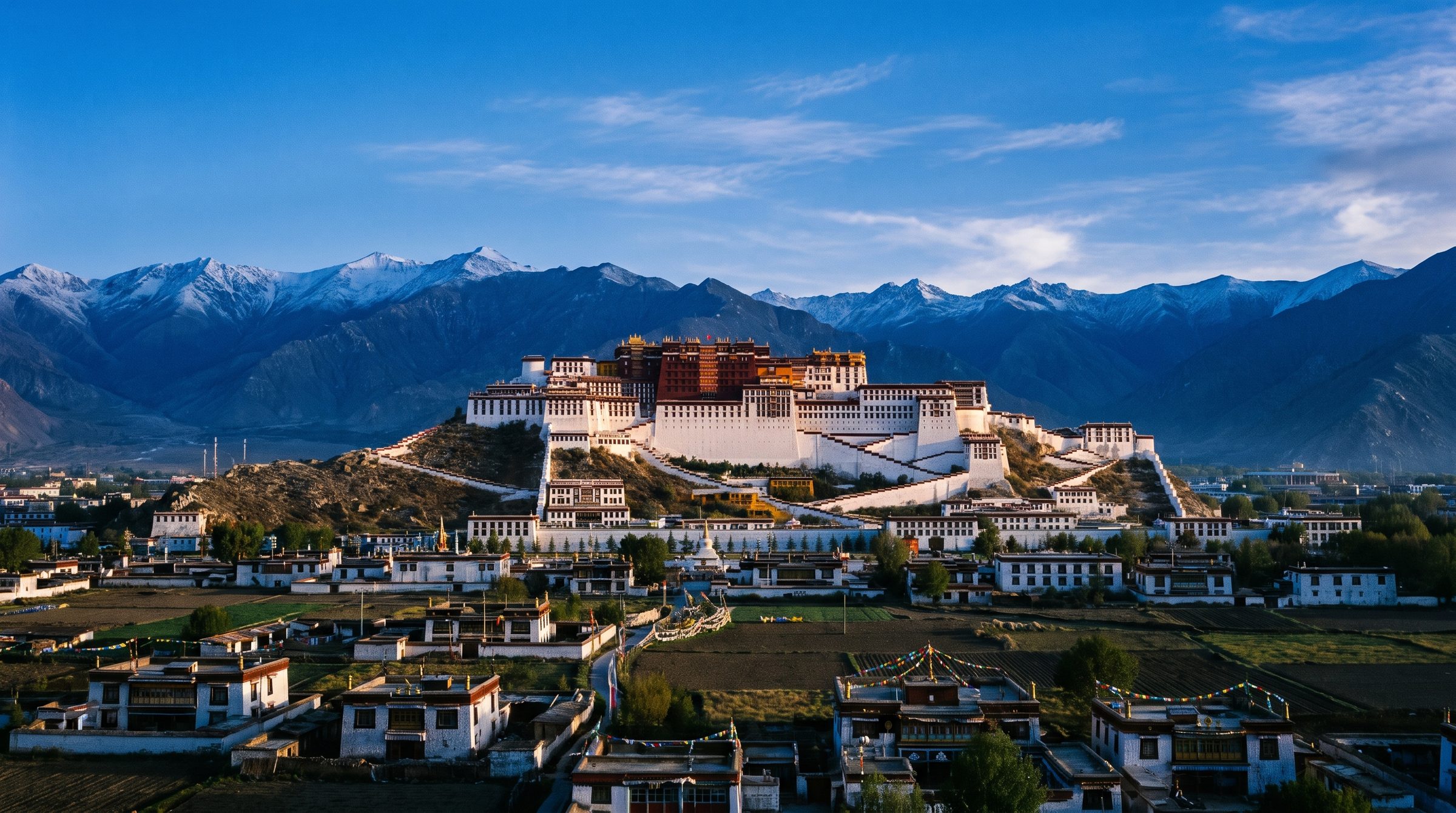 Aerial view of the Potala Palace in Lhasa rising on its red hill at sunrise, with the Lhasa valley stretching into the distance and prayer flags fluttering on the rooftop