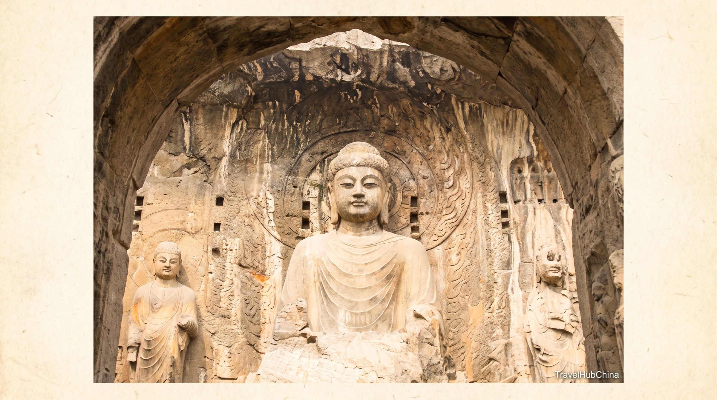 The Vairocana Buddha statue inside the Fengxian Temple niche at Longmen, with attendant disciples, heavenly kings, and Vajrapani guardian figures carved in high relief on the cliff face