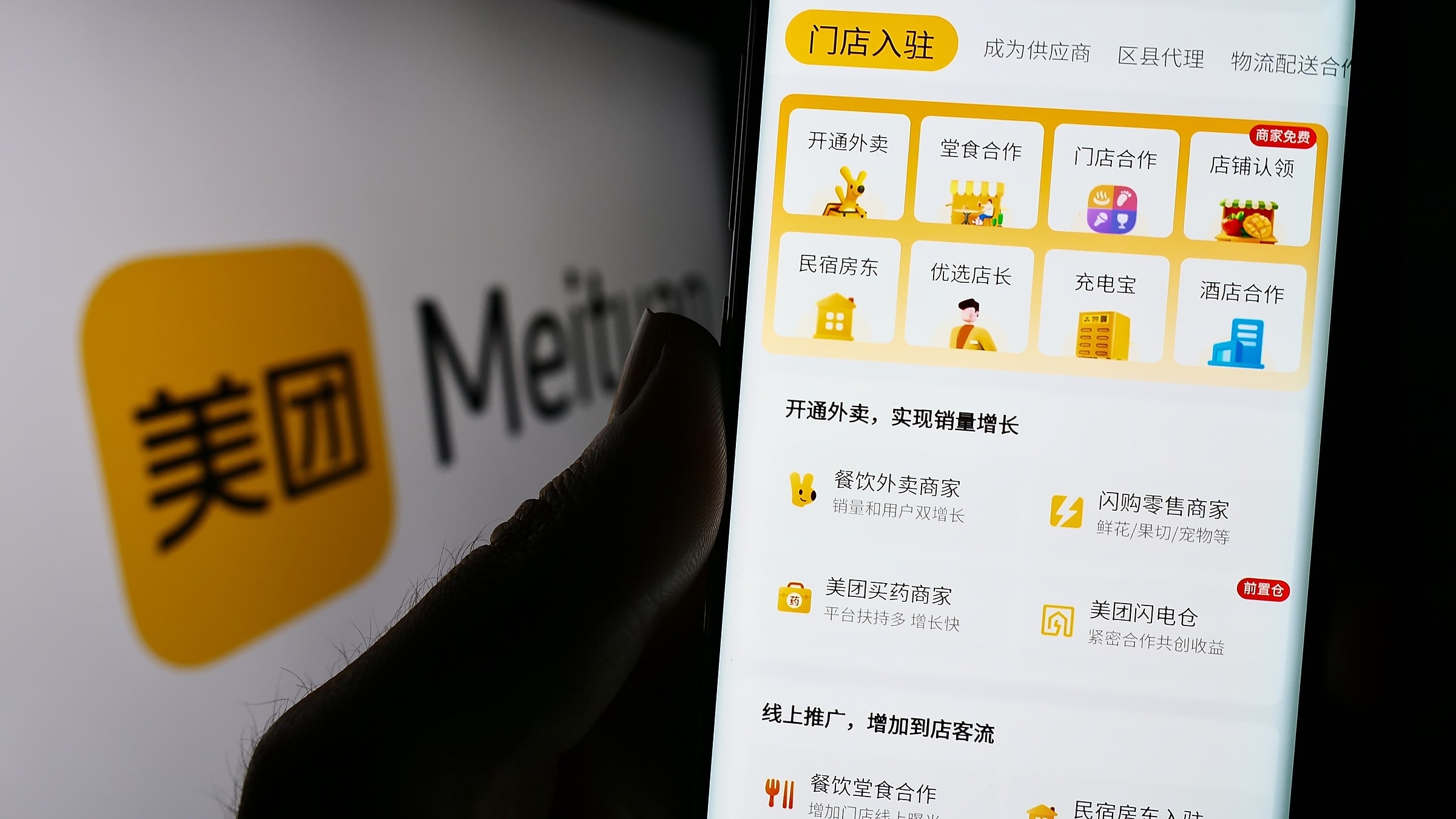 Meituan (美团) yellow app interface shown on a phone with hand holding it